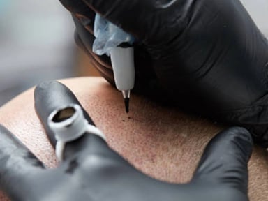Tattoo artist using a tattoo machine on scalp